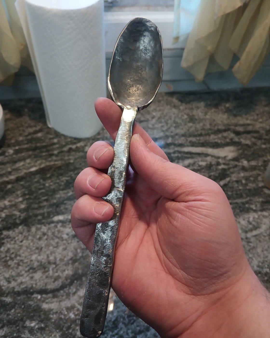 Hand holding a forged spoon